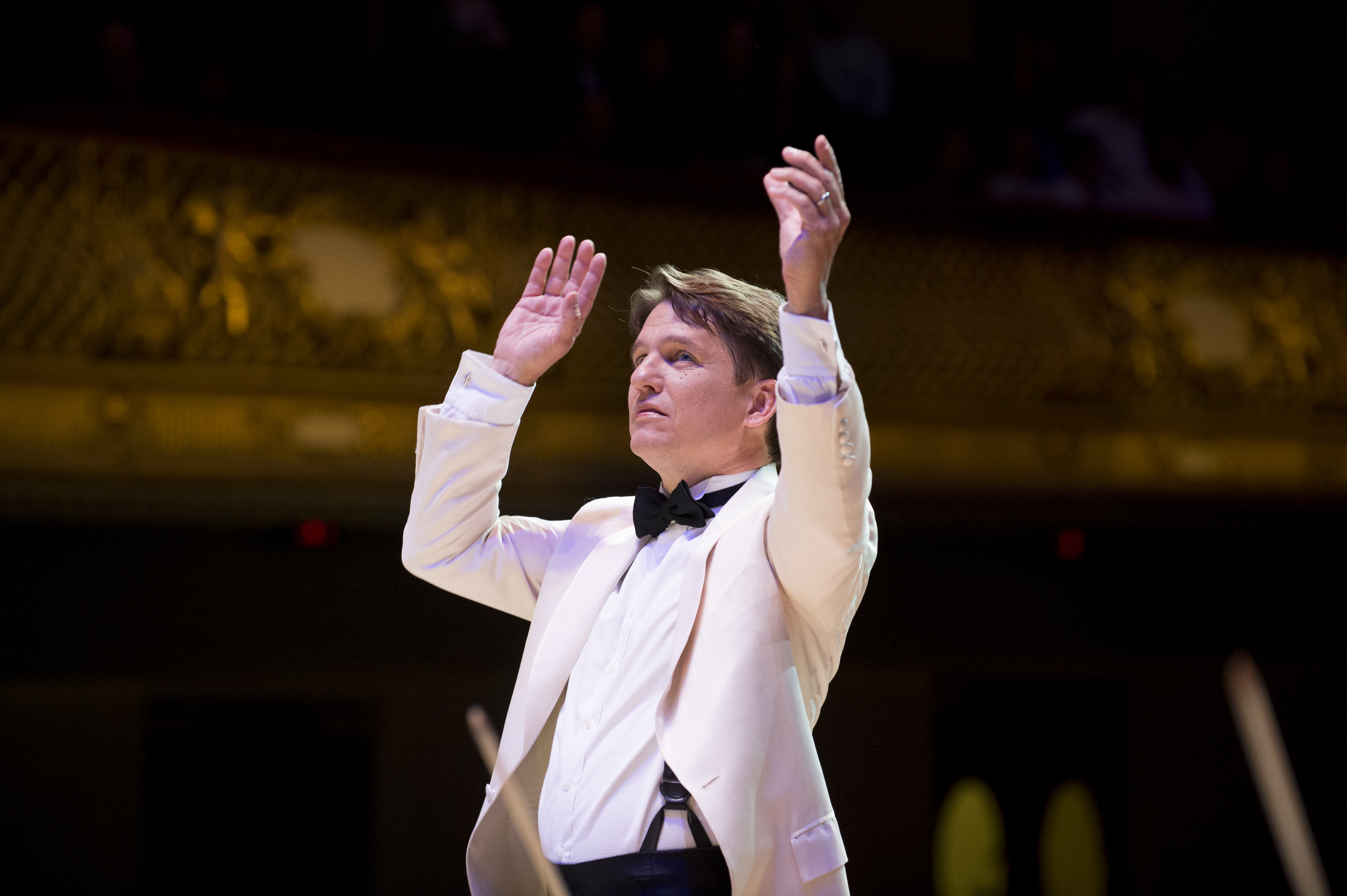 Keith Lockhart in a white tuxedo jacket conducts the Boston Pops at Symphony Hall.