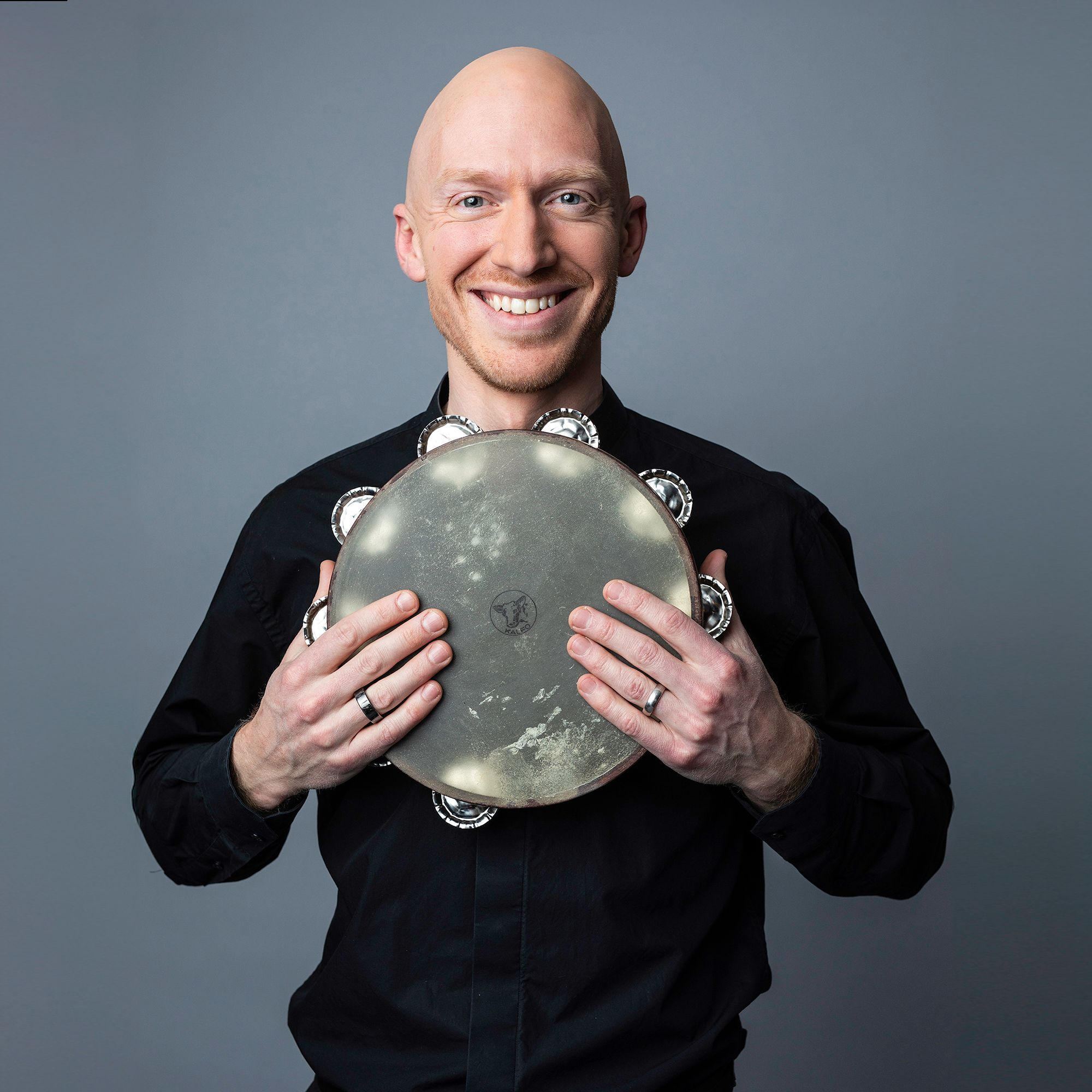 Matthew McKay headshot holding a tambourine