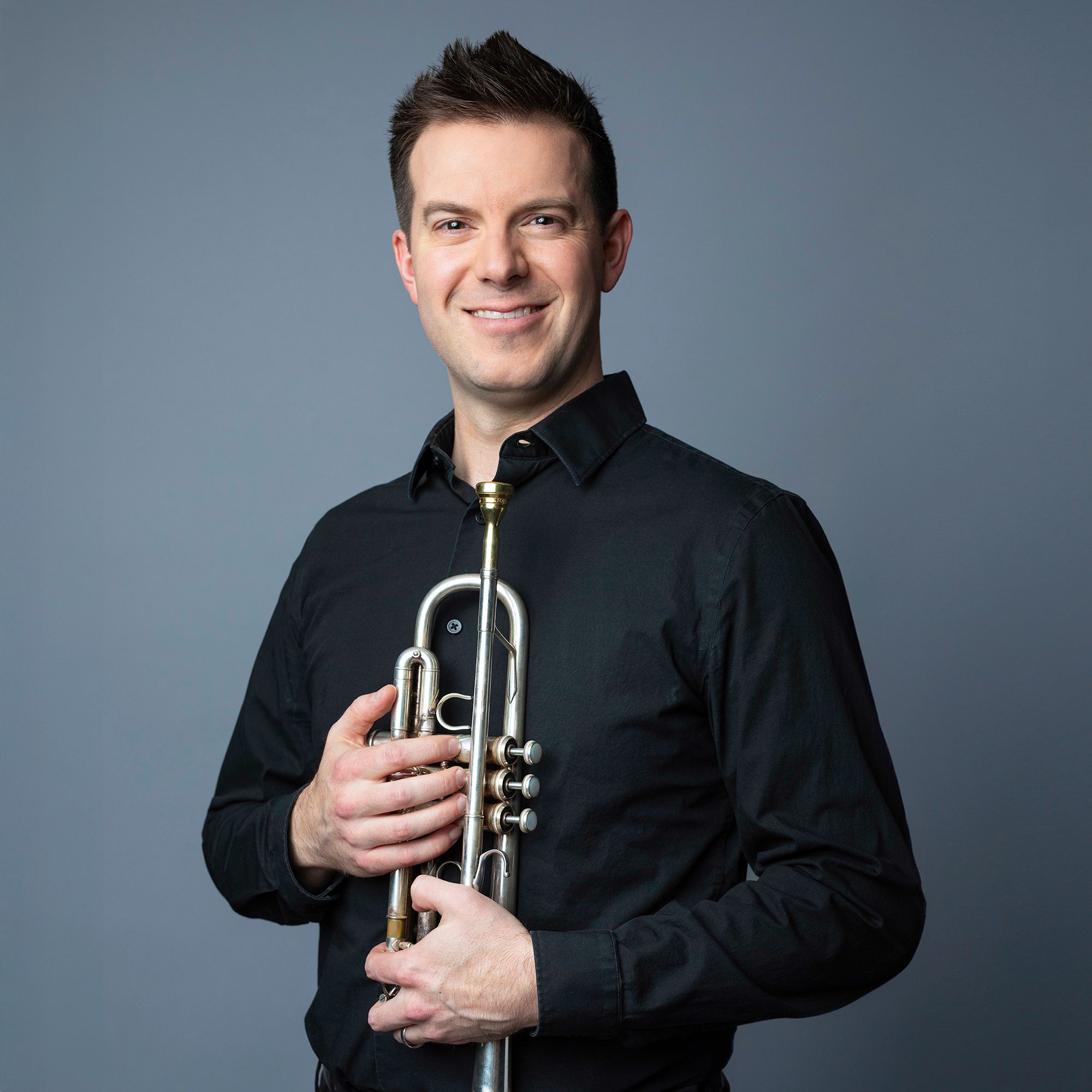 Thomas Siders headshot with trumpet