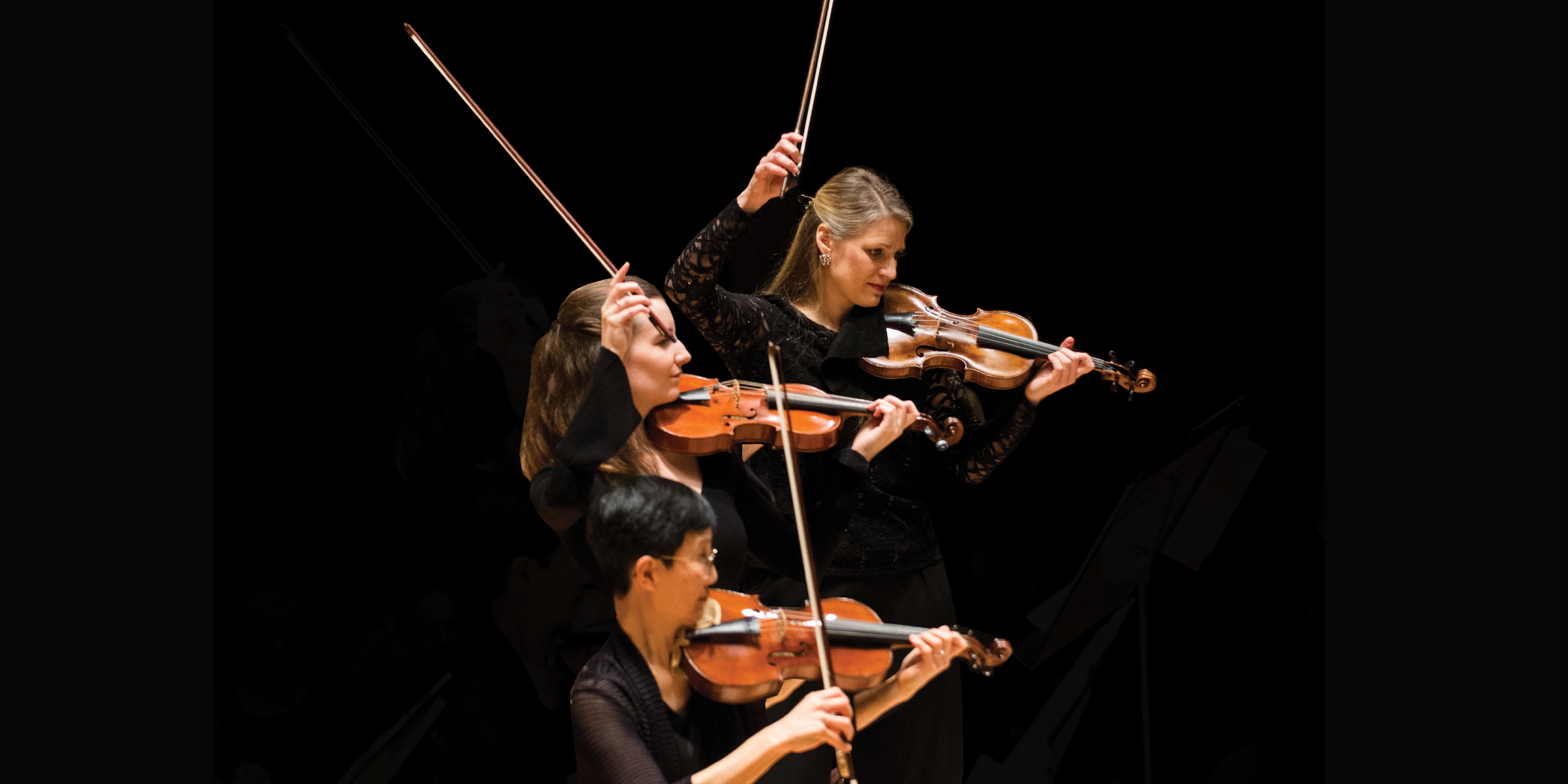 Three female violinists with their bows in the air