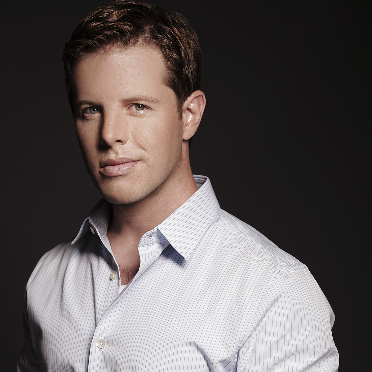 headshot of a man wearing a white striped button down shirt