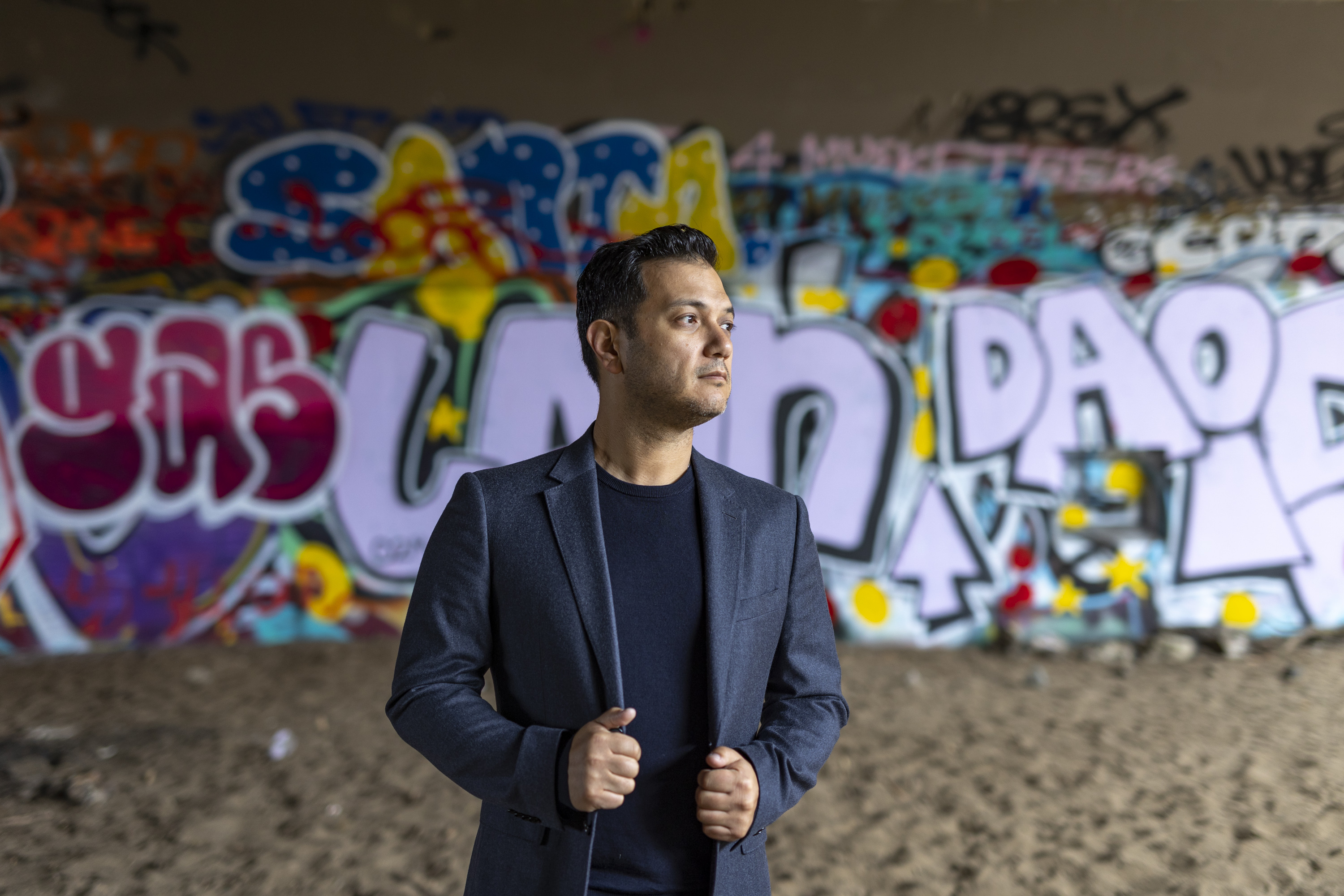 Nicholas Phan standing in front of a wall covered in graffiti