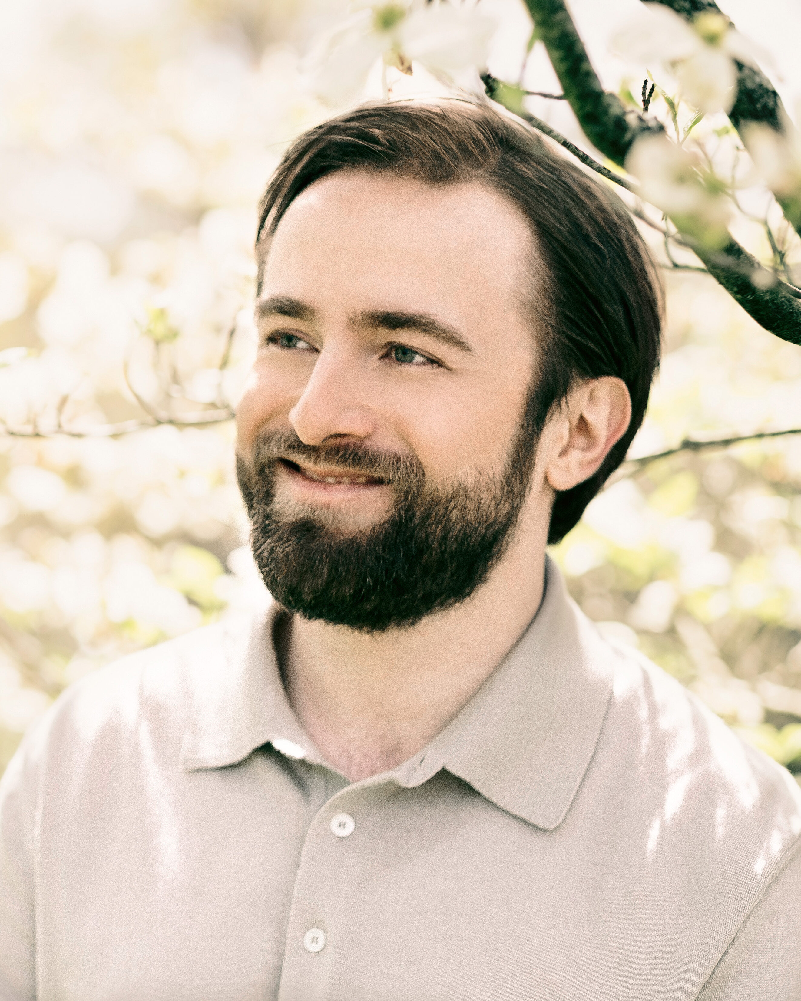 Daniil Trifonov in front of flowering trees, smiling