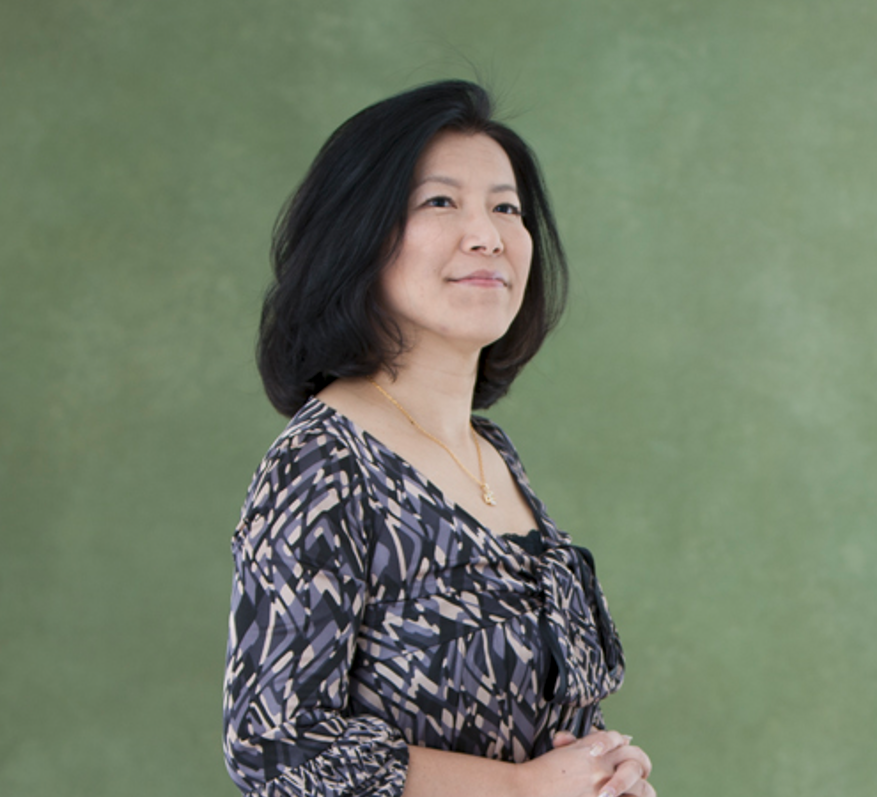 Yoko Shimomura standing in front of a green background