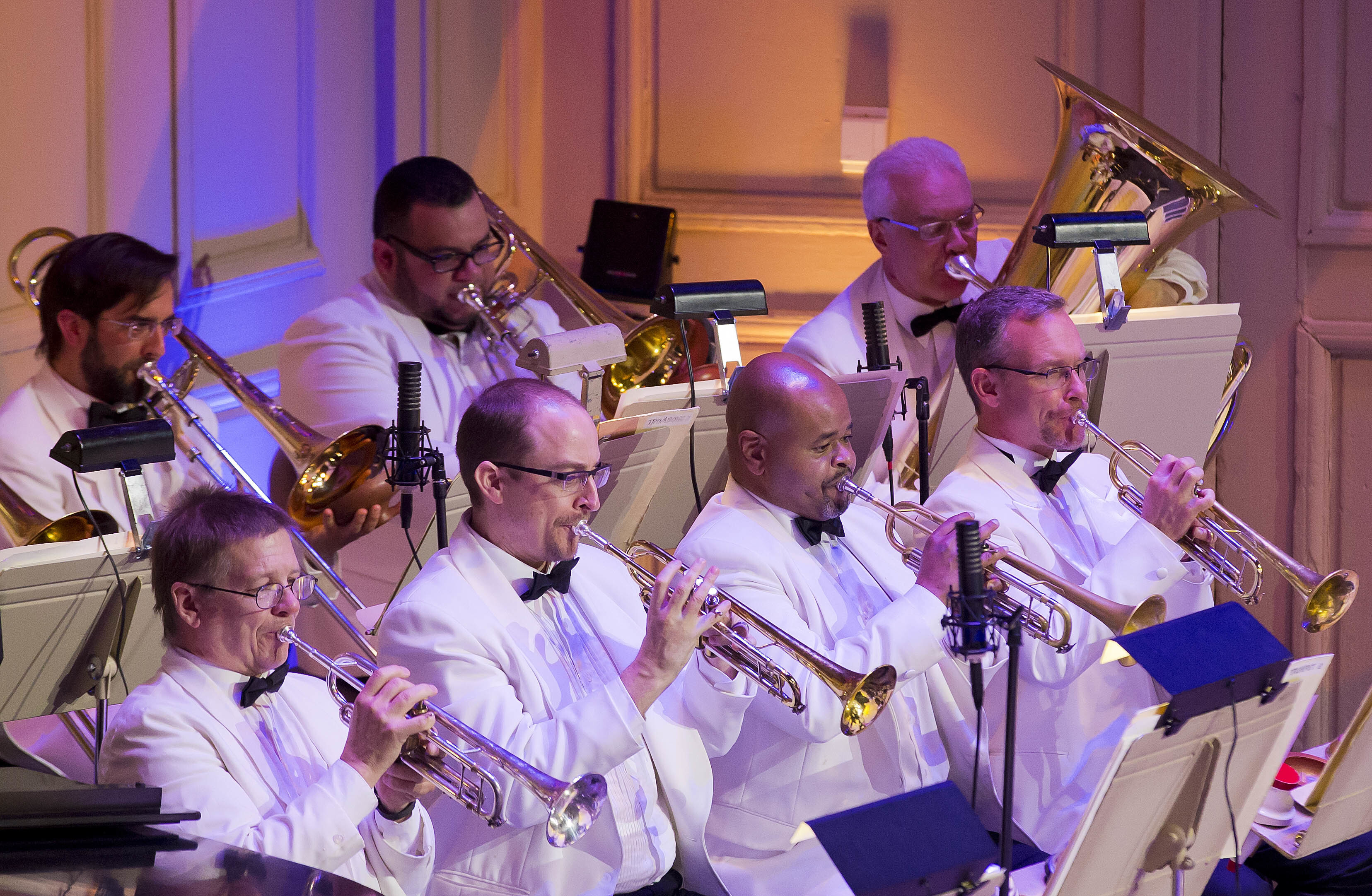 A group of brass players, all dressed in white tuxedos, play in a Pops concert in Symphony Hall
