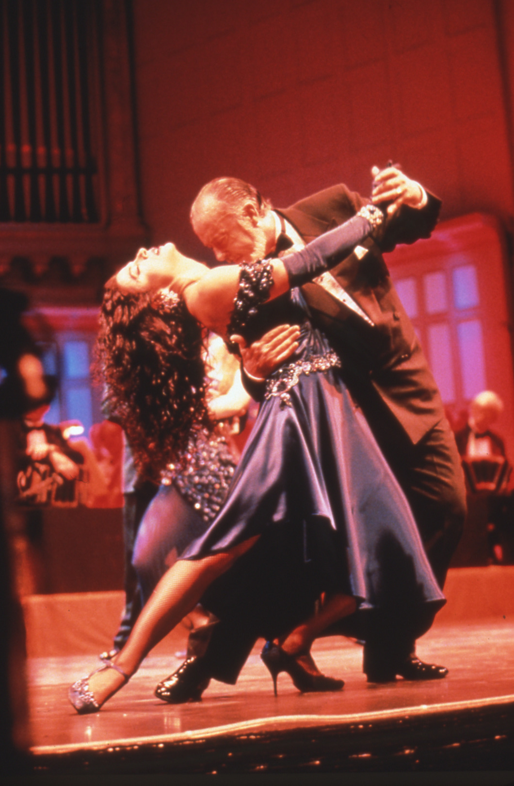A pair of dancers in a sweeping tango pose (legs outstretched) on Symphony Hall stage