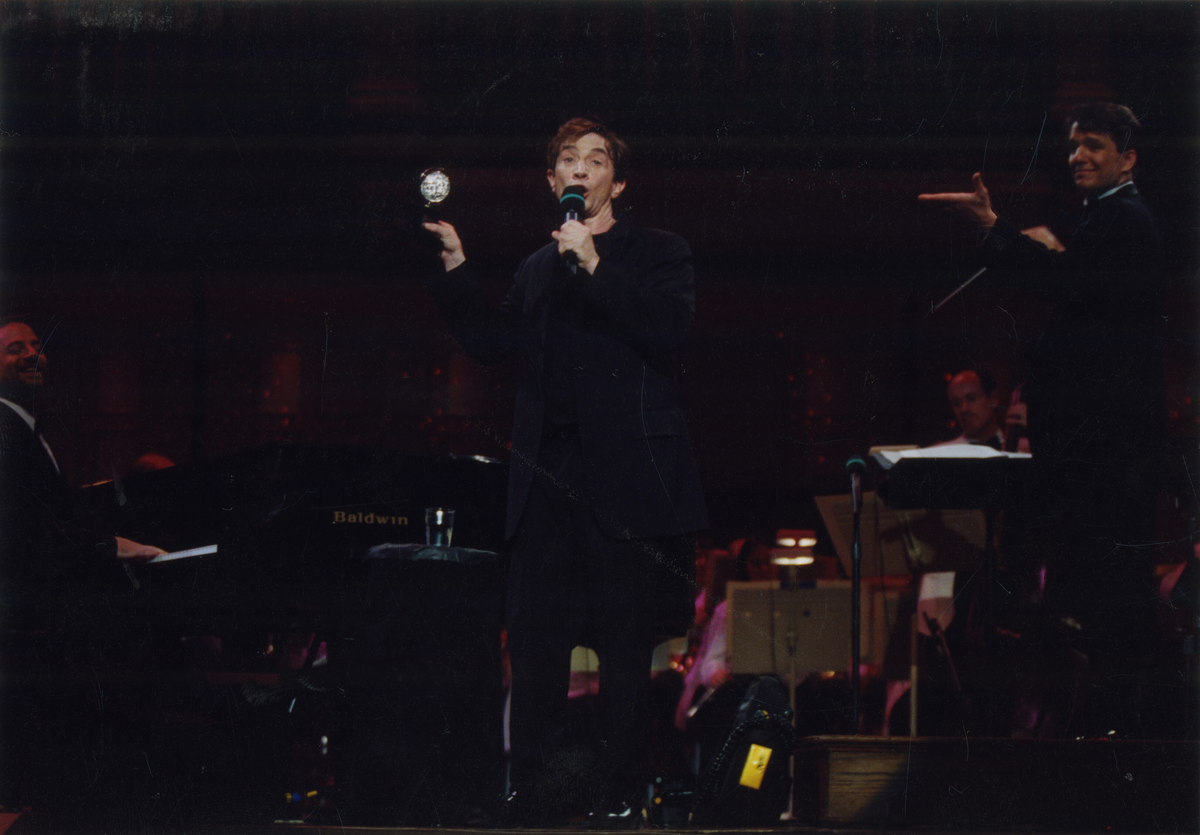 Guest soloist Martin Short holds a microphone on stage while Keith Lockhart gestures towards him
