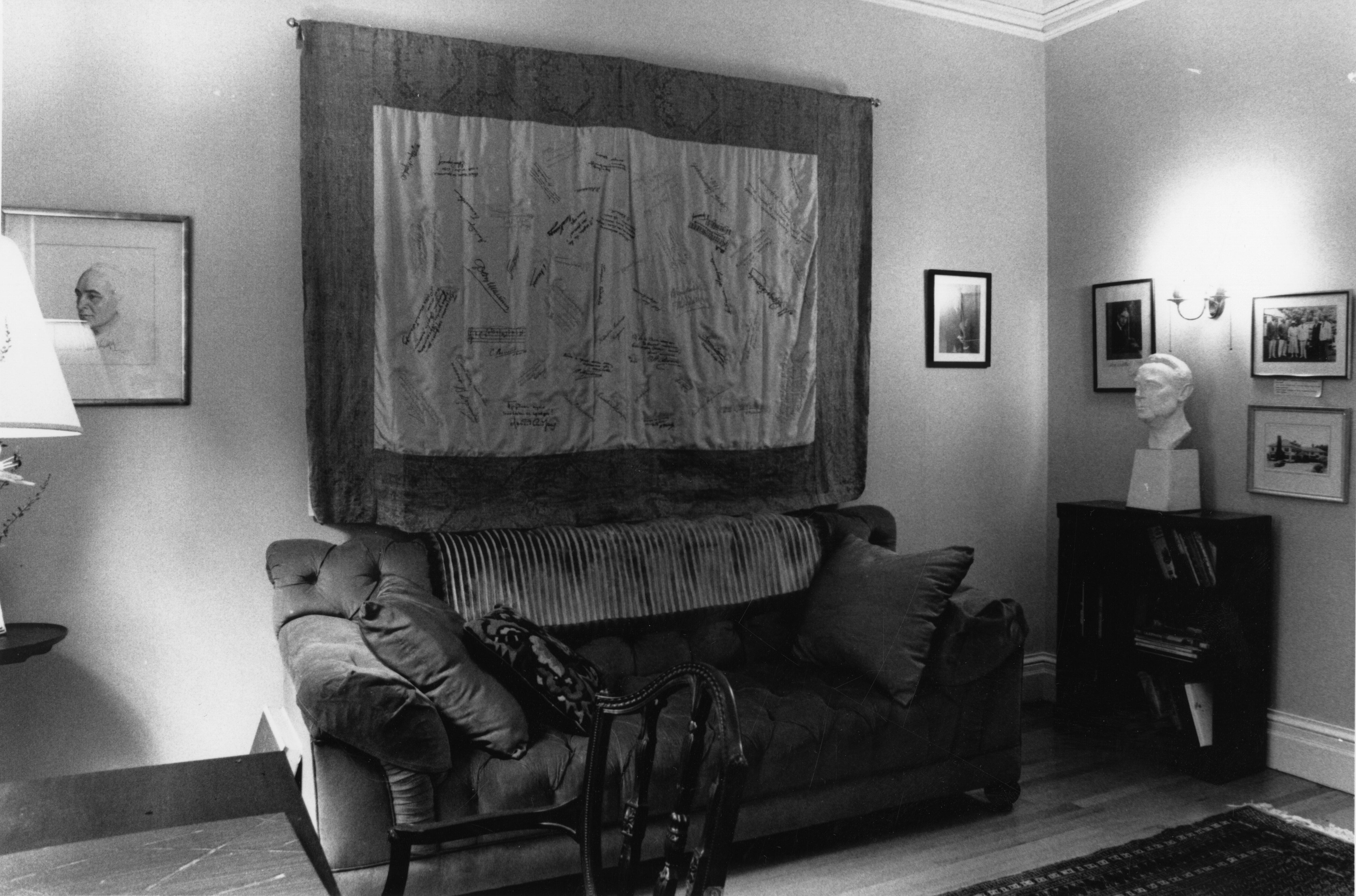 Interior of Koussevitzky's living room with quilt hanging on the wall behind a couch and between two prints
