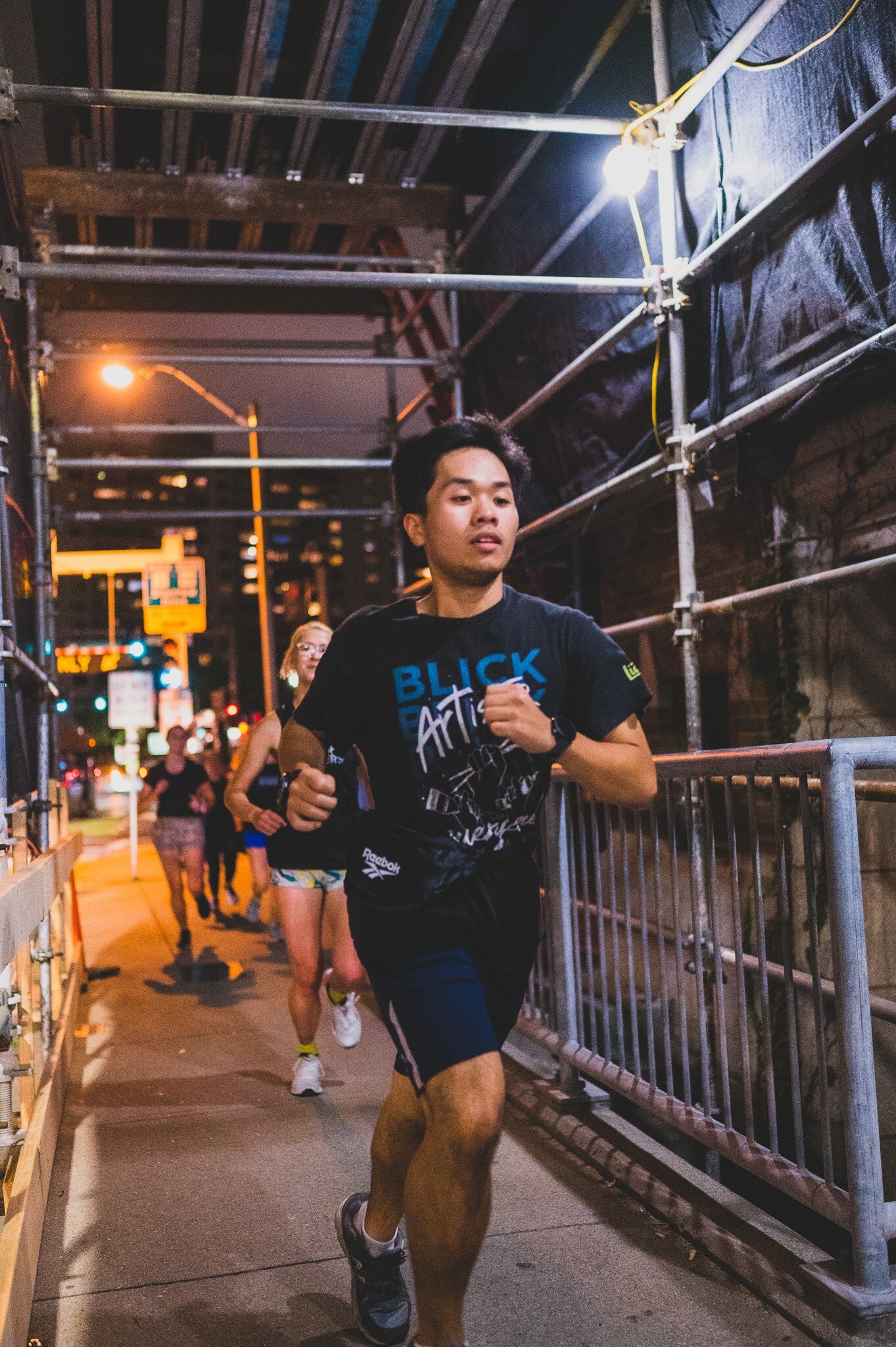 A man runs under outdoor scaffolding at night