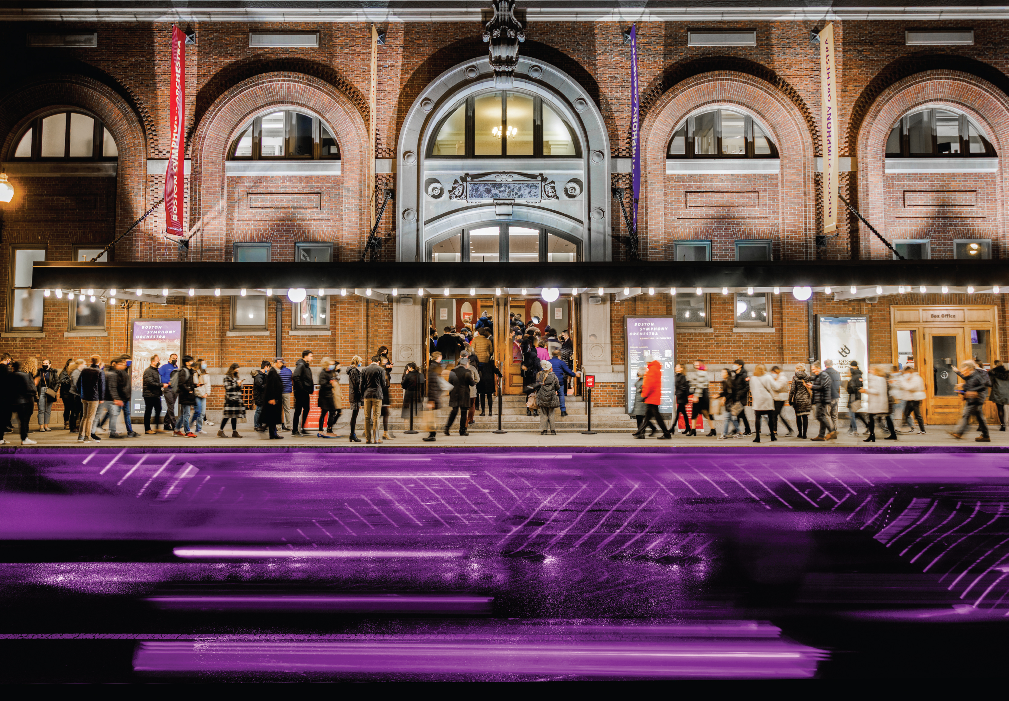 Crowds line up outside of Symphony Hall before a concert as a blur of traffic drives past, tinted purple via Photoshop