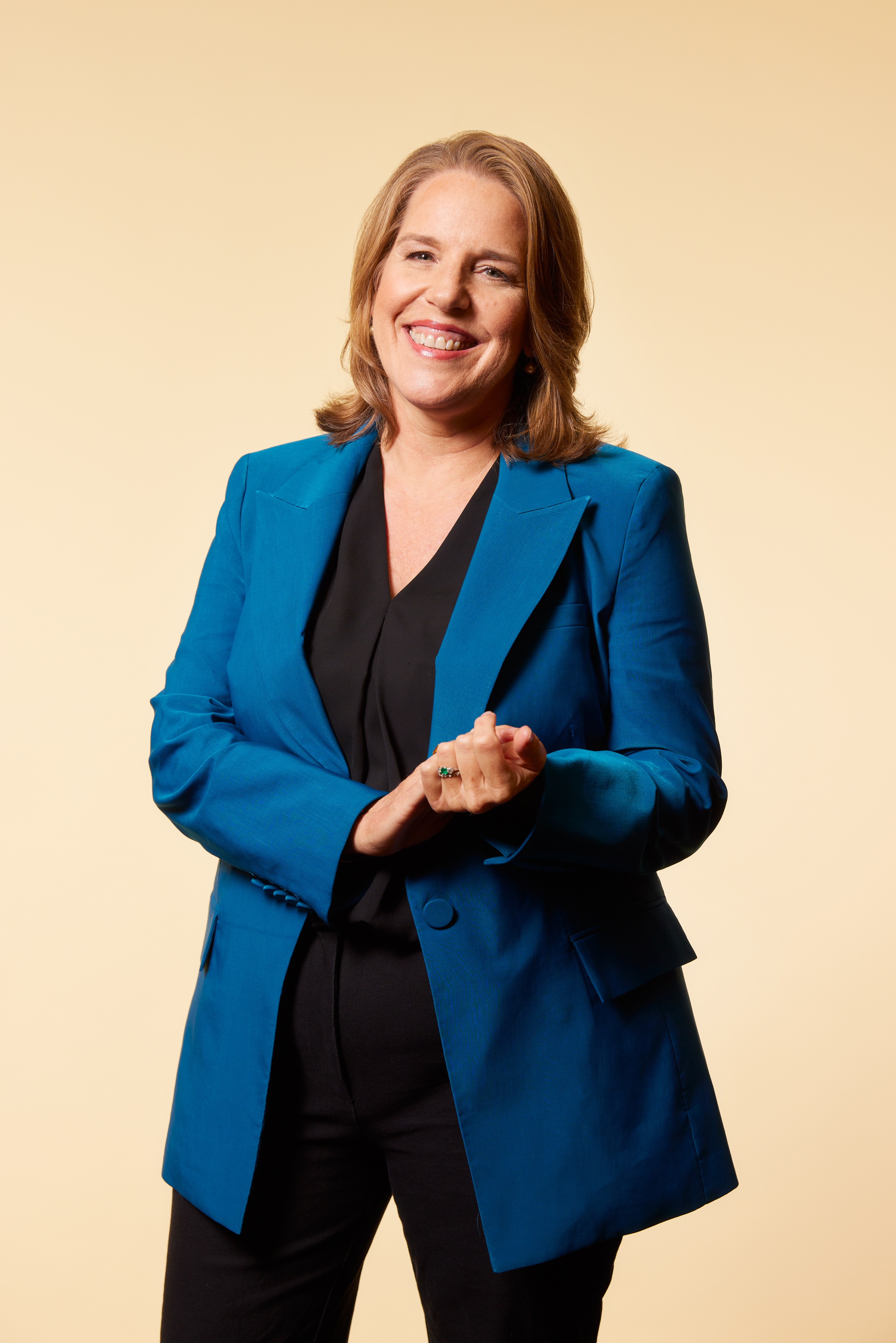 A photo of Gail Samuel, who has light brown hair and wears black pants and a long blue blazer