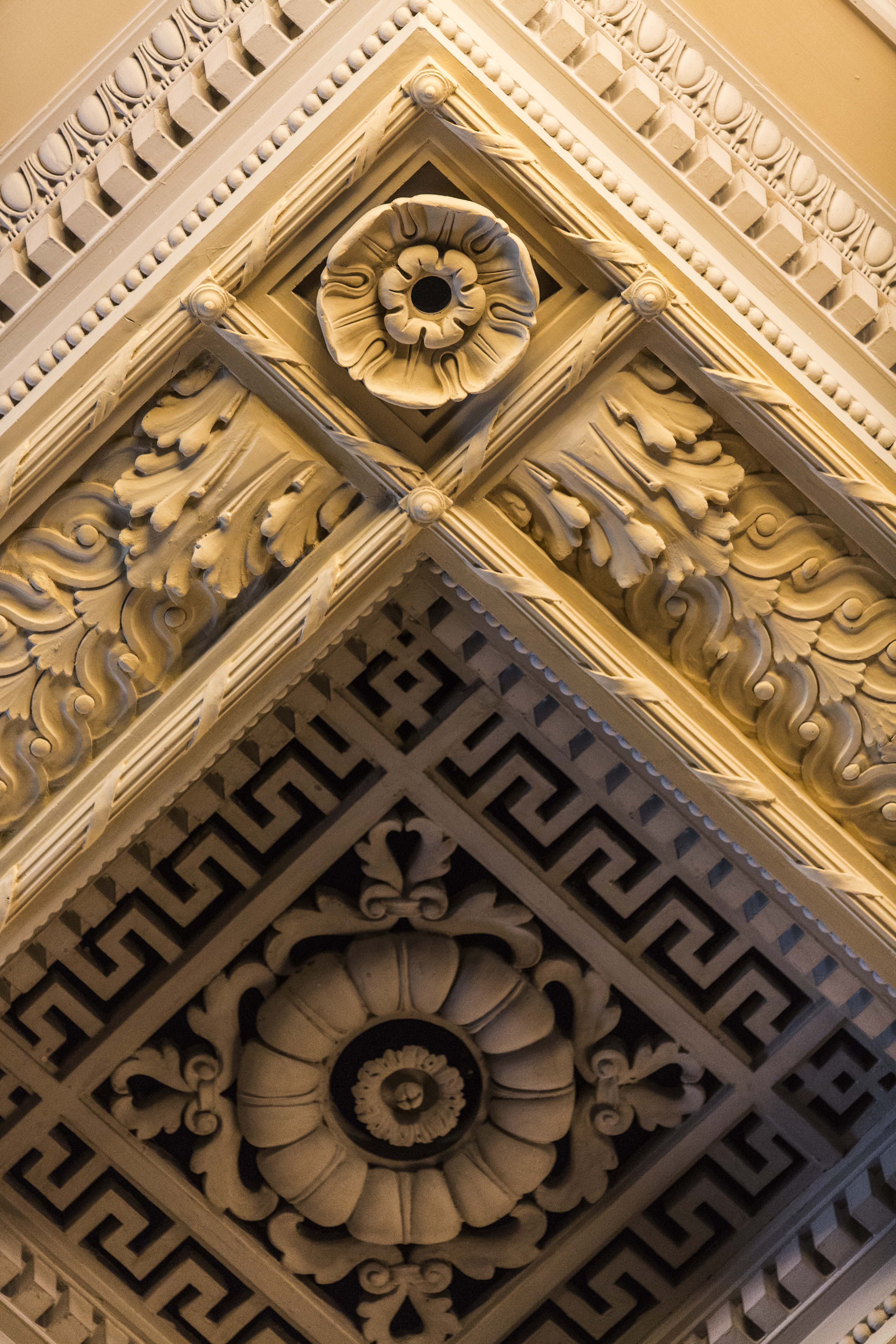 A close-up view of cream-colored, intricate molding backstage at Symphony Hall with floral and geometric shapes