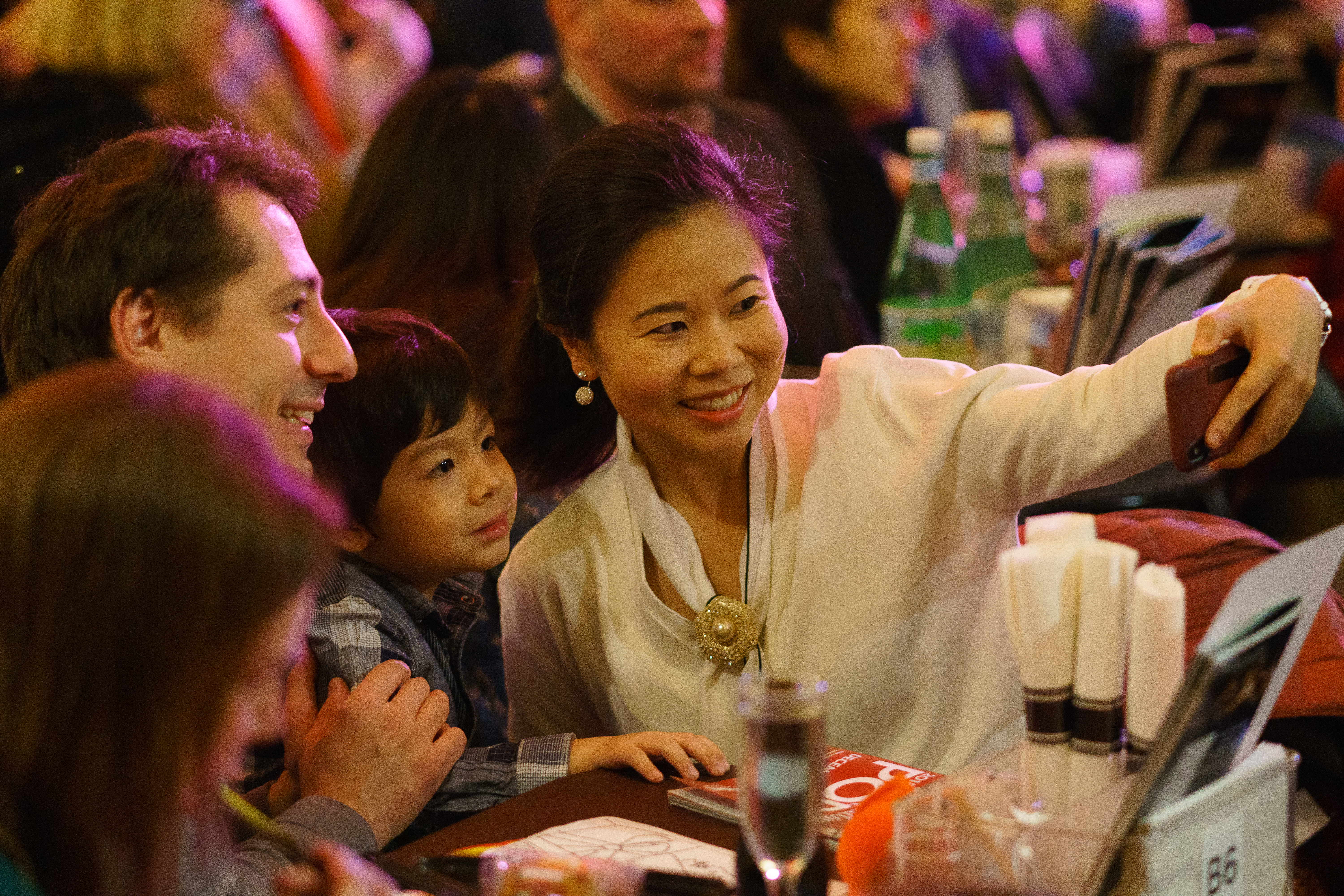12.22.18 a mutliracial family takes a photo of themselves at a table during a Holiday Pops performance