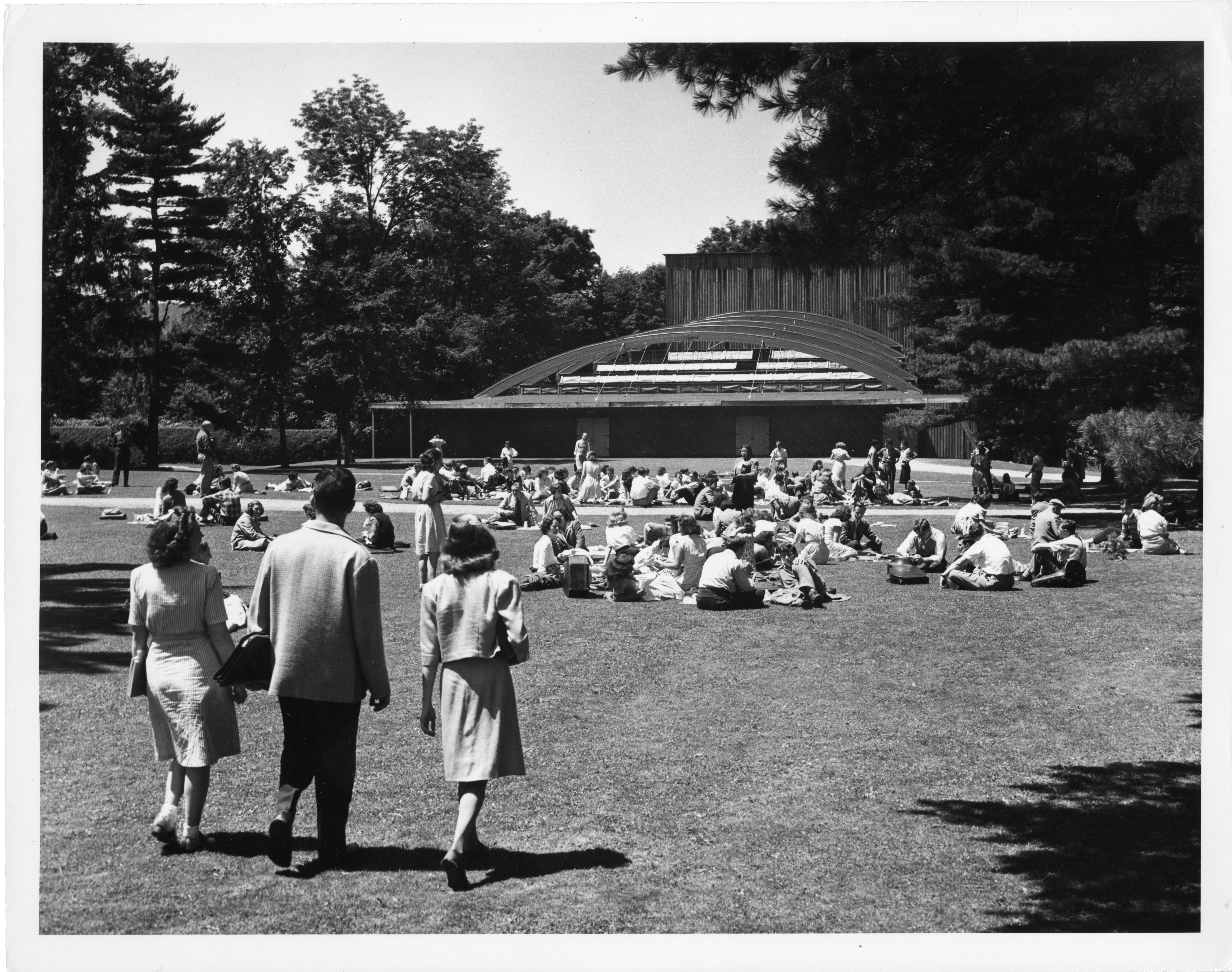 Students walk away from camera, towards a theater building at Tanglewood