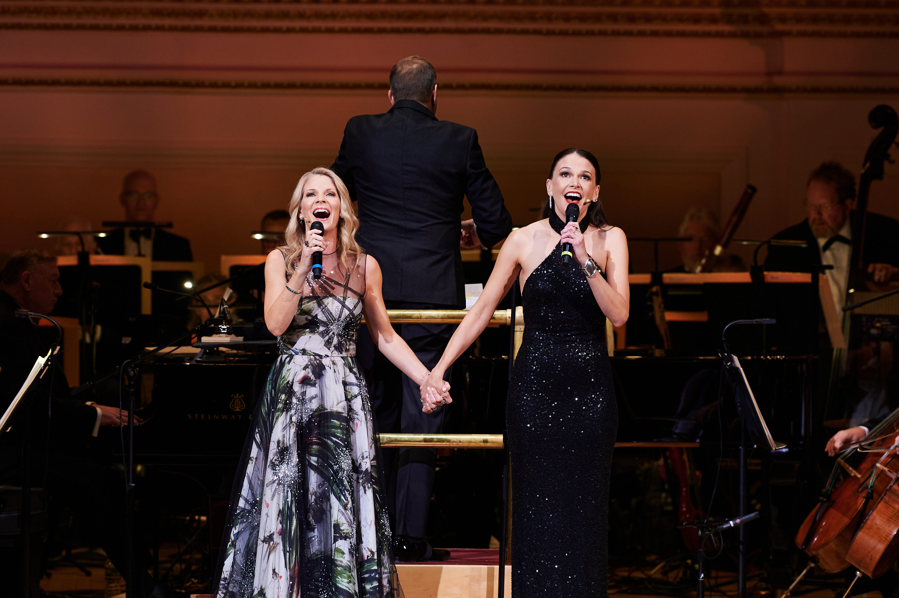 Kelli O'Hara and Sutton Foster holding hands while singing on stage