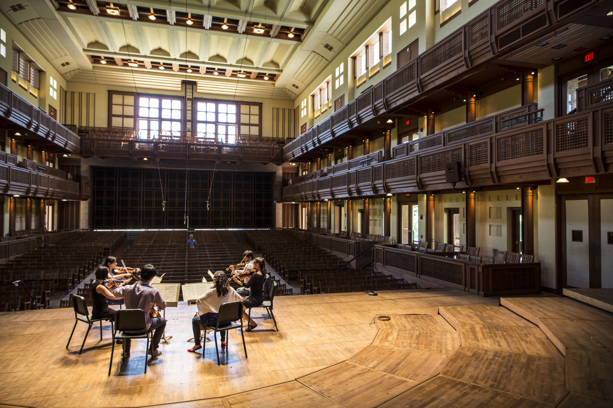 A string sextet rehearsing onstage at Ozawa Hall while a single listener watches them from the audience.