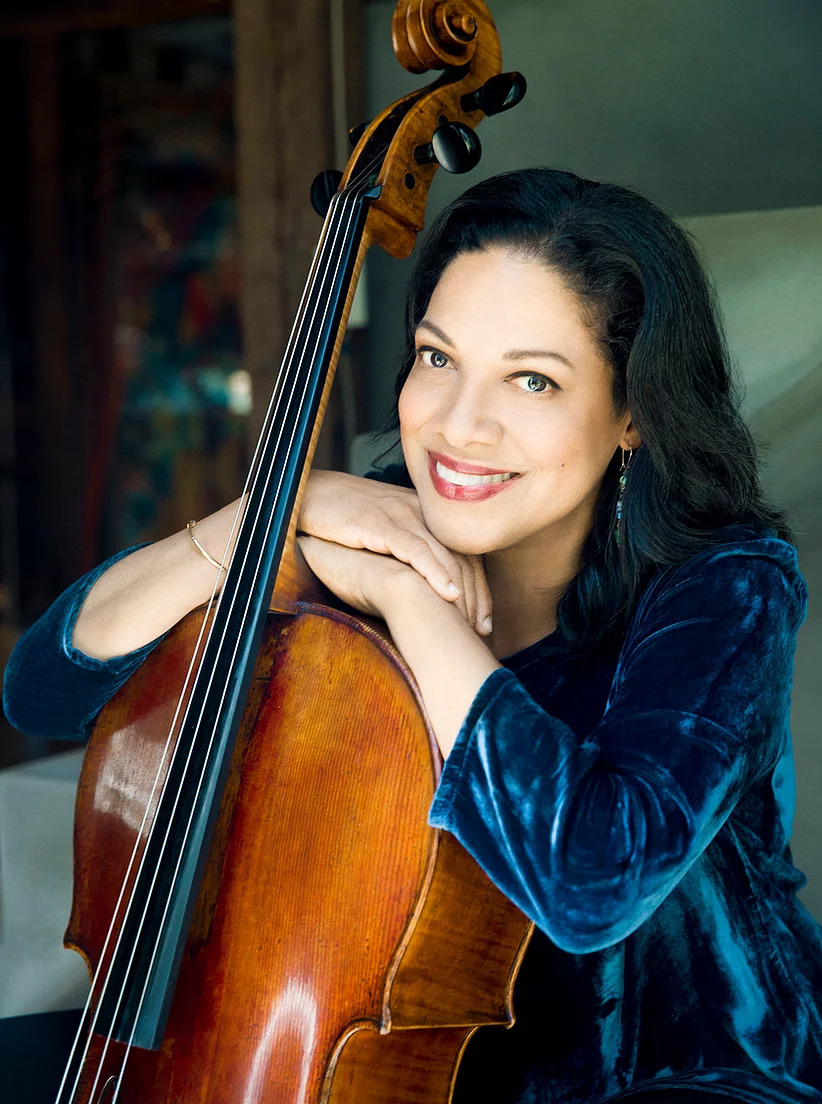 Astrid Schween headshot resting her hands and chin on her cello