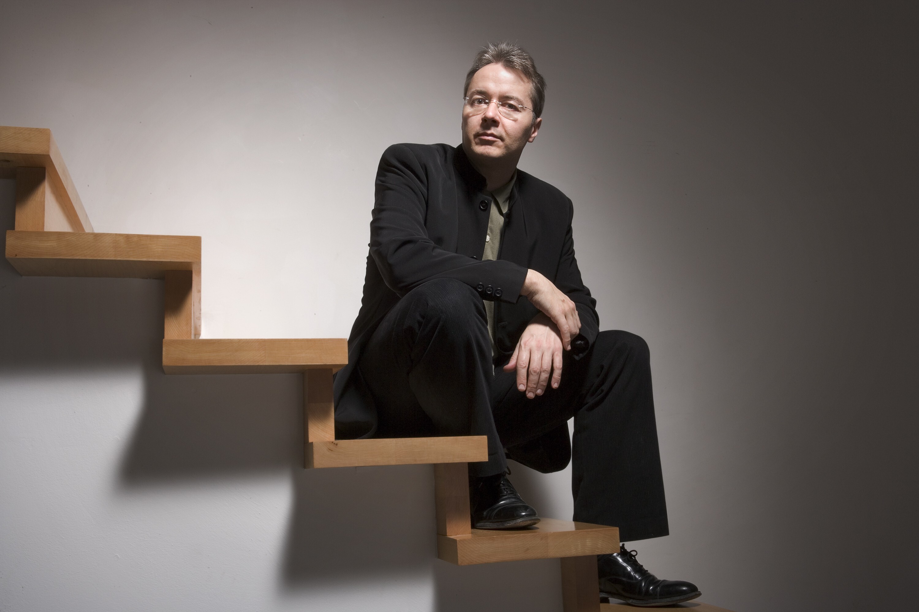 Stefan Asbury sitting on wooden stairs