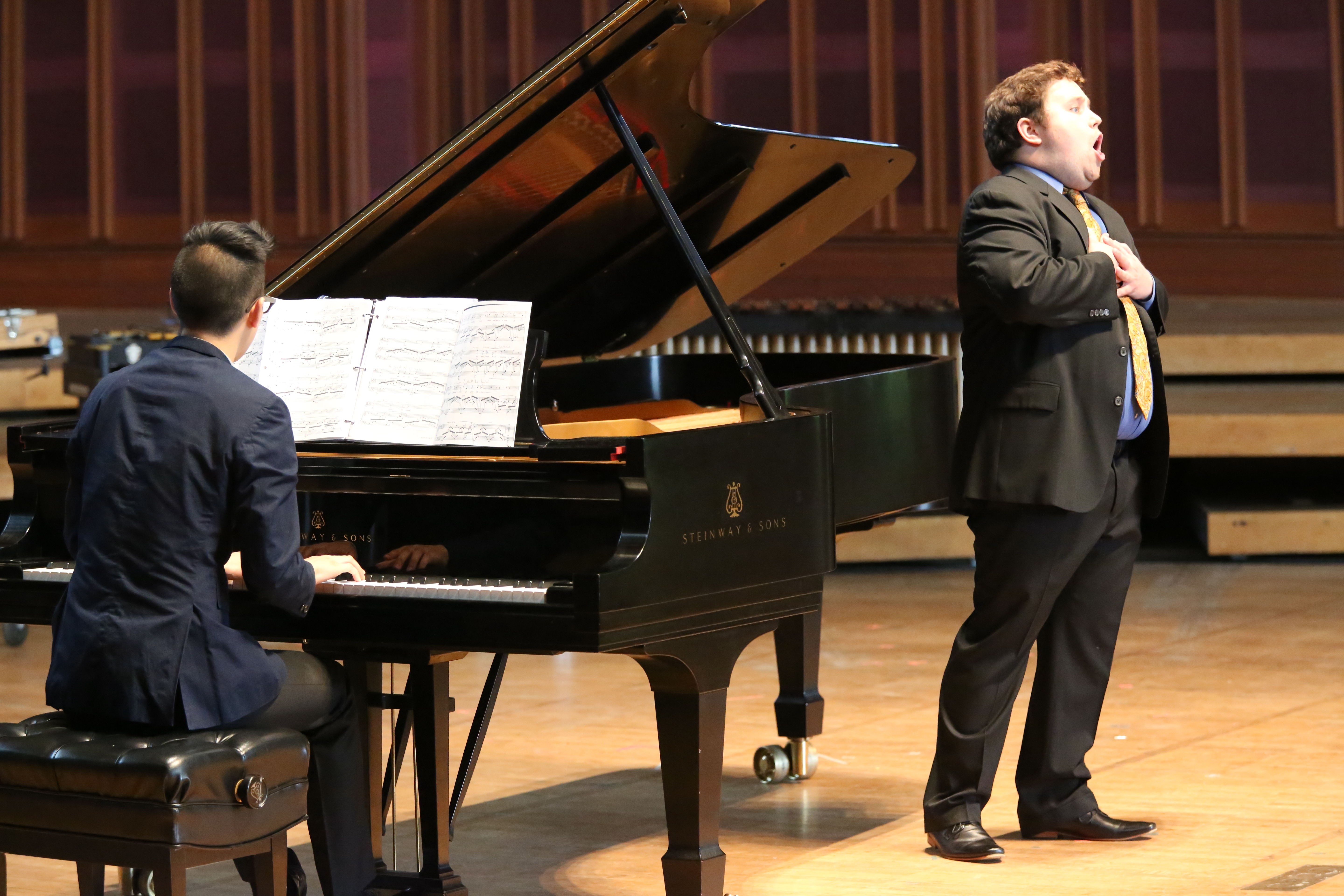 A singer performing onstage with a pianist.