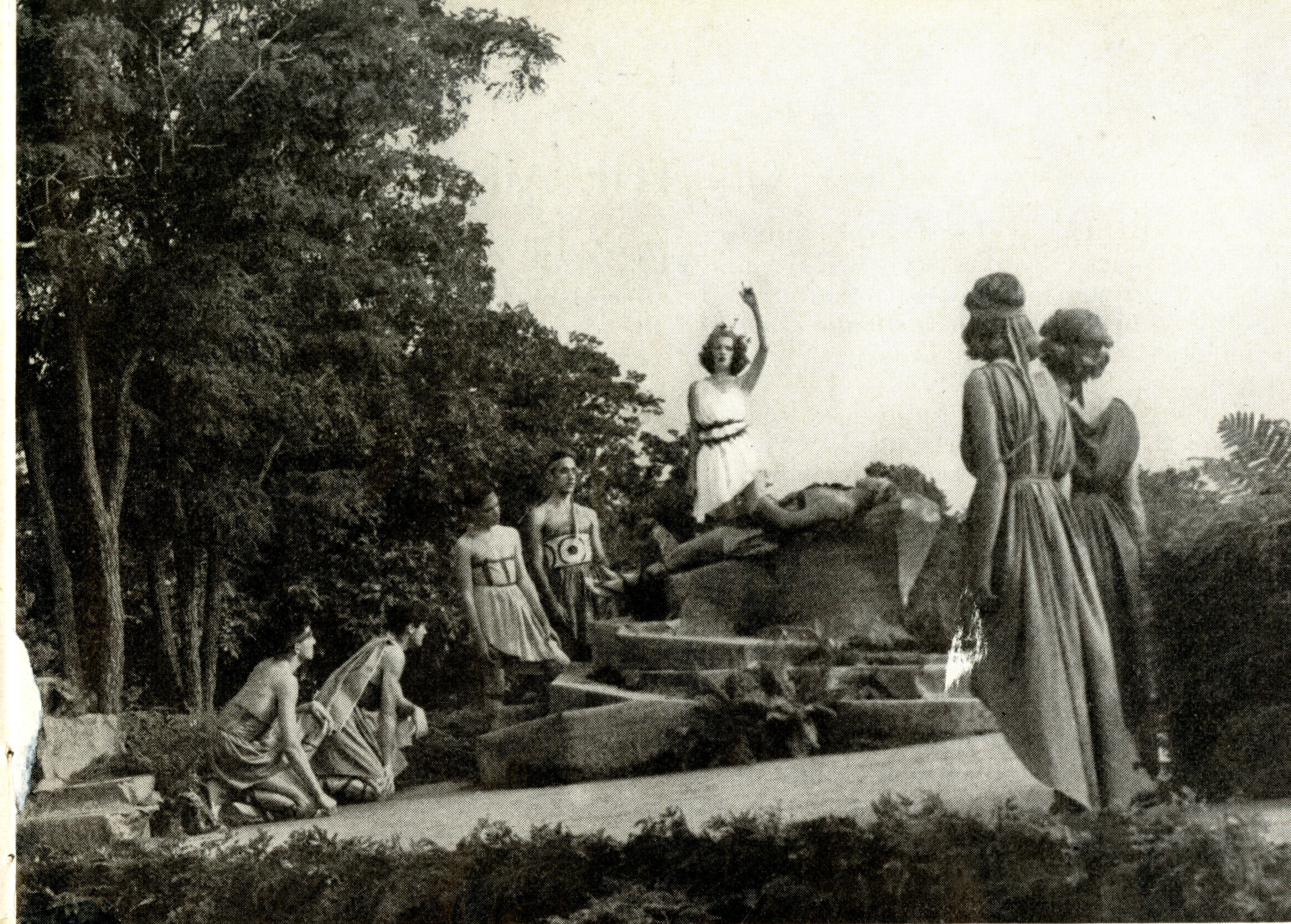 Students in costume gesture outdoors as they perform an opera
