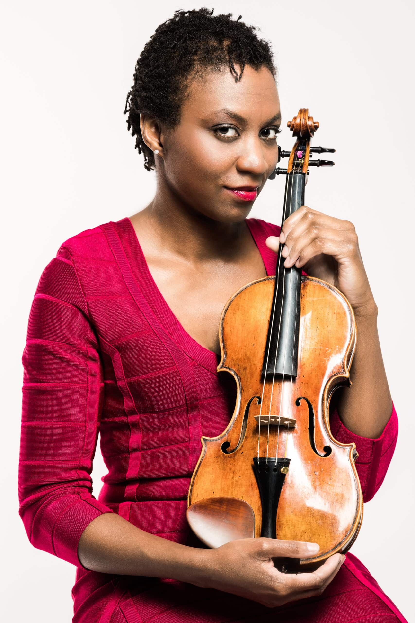 Tai Murray wearing a red dress holding her violin