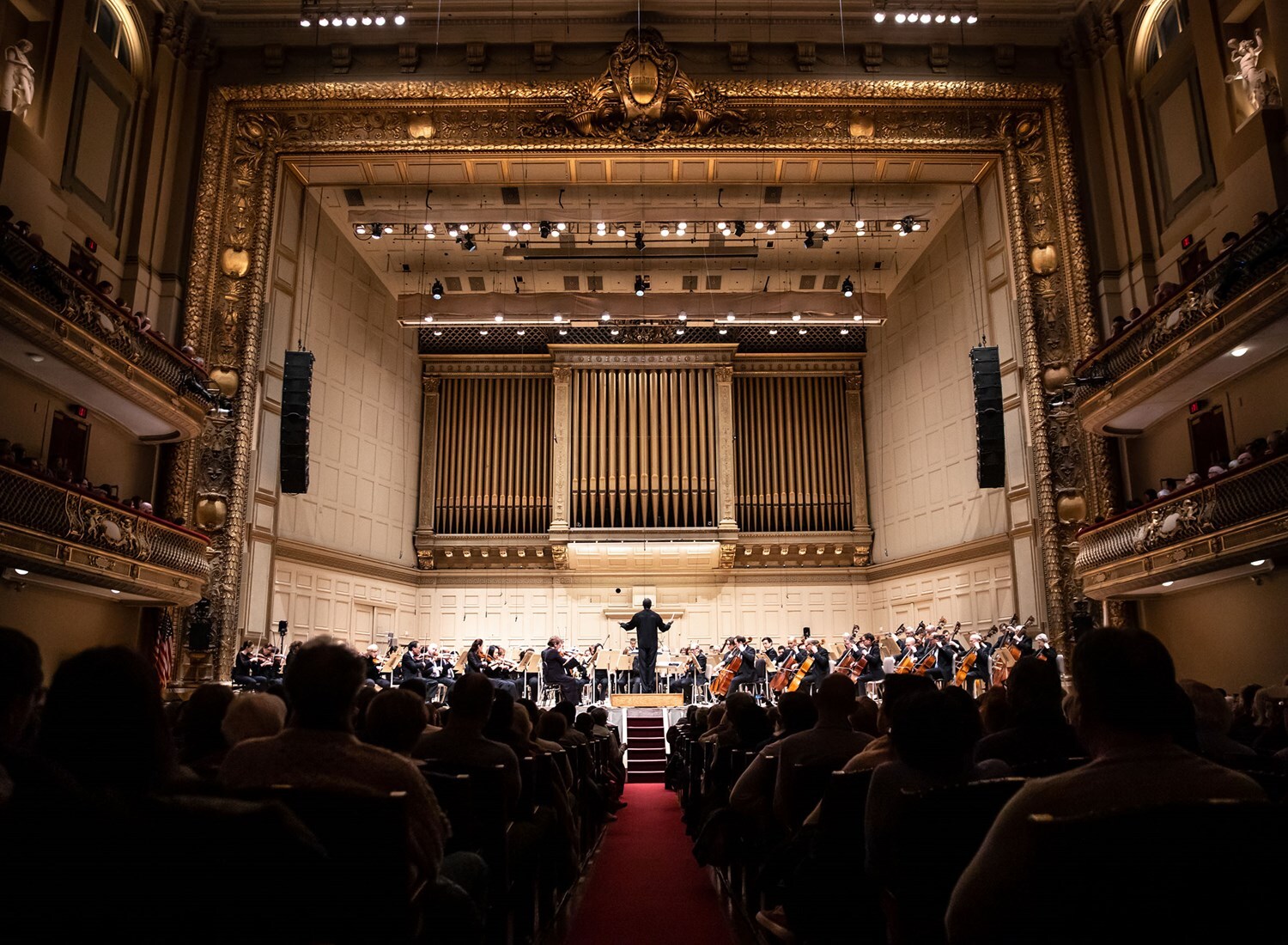 Looking down the center aisle of Symphony Hall with a full house and stage