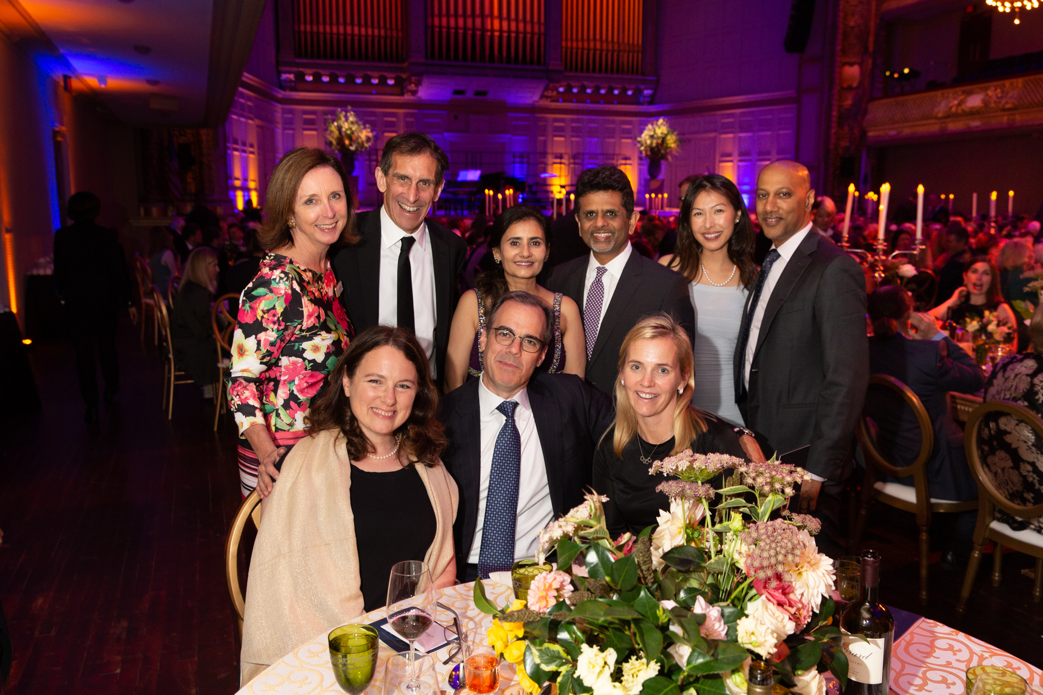 A group of people sitting at a table dressed up at an event.